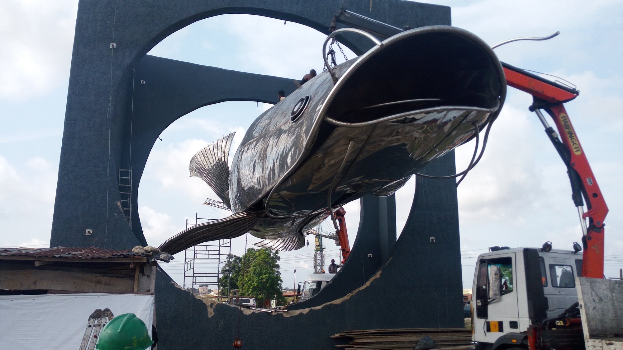 Eja Nla: the steel fish lifted by crane on site.